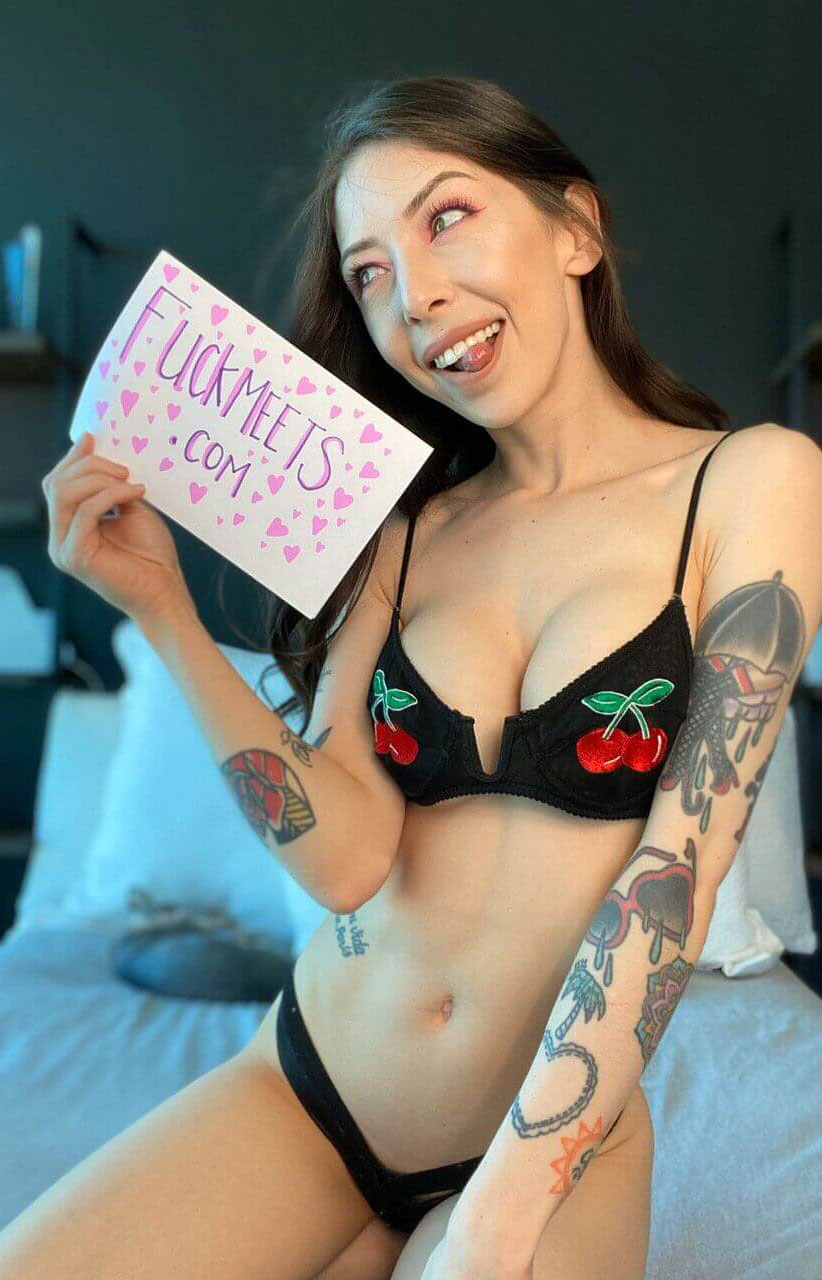 brunette with fake boobs holding fuckmeets sign to search local sex nearby